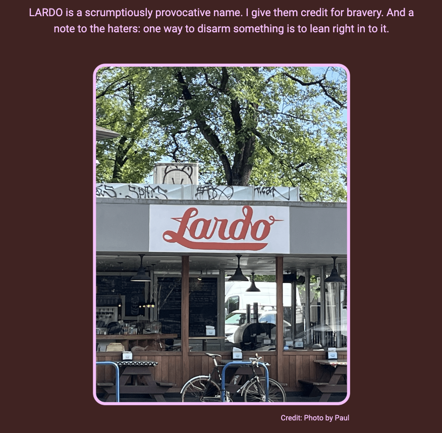 The image shows the exterior of a restaurant named 'Lardo' with a clear view of the signboard above the establishment. The text above the image praises the name of the restaurant. Here is the alt text including all of the text that appears in the image:

"Photograph of a street-side restaurant with a large sign that reads 'Lardo' in cursive red lettering. The façade of the restaurant is partially visible with its interior slightly obscured by reflections. In front of the restaurant, there is a bicycle parked to the side. The text above the image states: 'LARDO is a scrumptiously provocative name. I give them credit for bravery. And a note to the haters: one way to disarm something is to lean right in to it.' The image is framed with a pink border, and the credit 'Photo by Paul' is located at the bottom right corner."